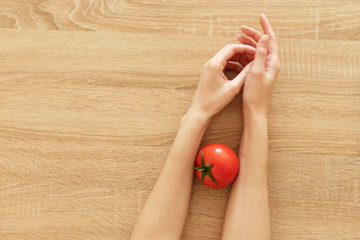 Juicy tomato in hands on wooden background tomato-ˈmätō,təˈmātō Перекл