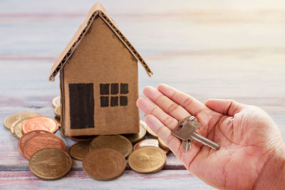 Close-up of hand holding small house against building
