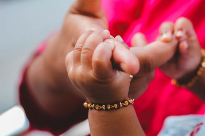 Cropped image of baby girl holding mother hand