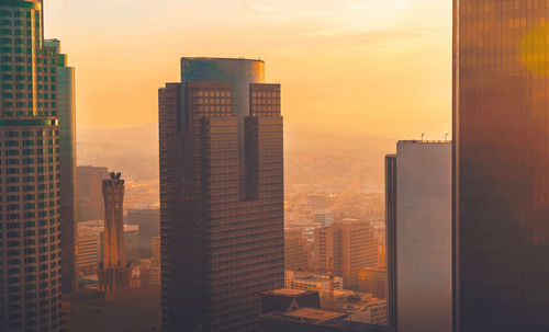 Modern buildings in city against sky during sunset