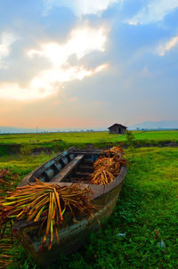 Abandoned boats on field against sky during sunset