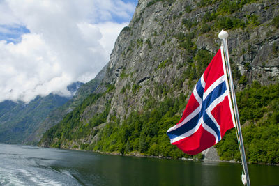 Scenic view of flag by mountains against sky