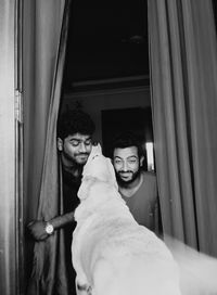 Young male friends playing with dog amidst doorway at home