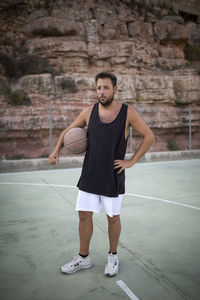 Portrait of man holding basketball while standing in court