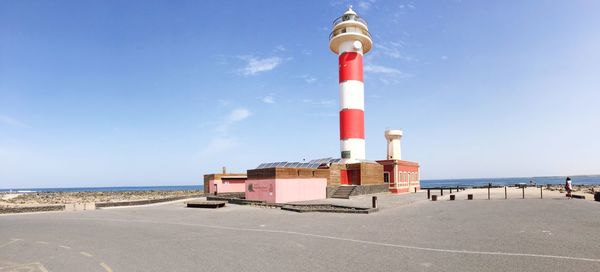 Lighthouse by sea against sky