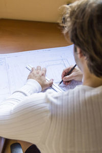High angle view of architect drawing blueprint at desk