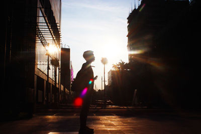 Silhouette man standing on street during sunset