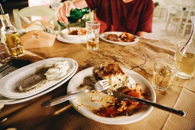 Midsection of man pouring drink while sitting at table in restaurant