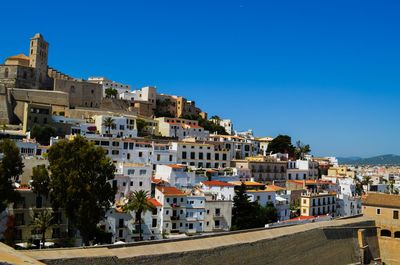 Buildings in city against clear blue sky