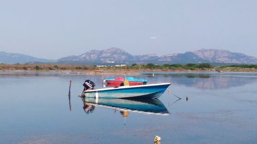 Boat moored on lake against sky