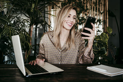 Woman using phone while sitting on table