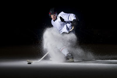 Man playing ice hockey against black background