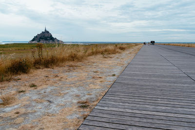 Footpath by sea against sky