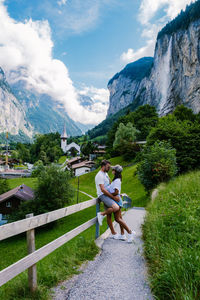 Rear view of couple sitting on mountain against sky