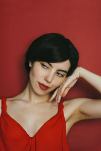 Portrait of a beautiful young woman against red background red lips make-up