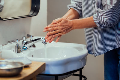 Midsection of man washing hands in bathroom