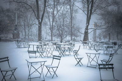 Snow covered tables and chairs in park