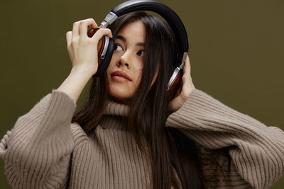 Portrait of young woman with eyes closed standing against wall