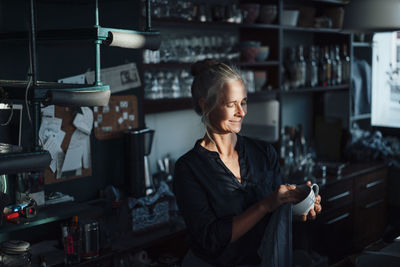 Female cafe owner cleaning cup in kitchen