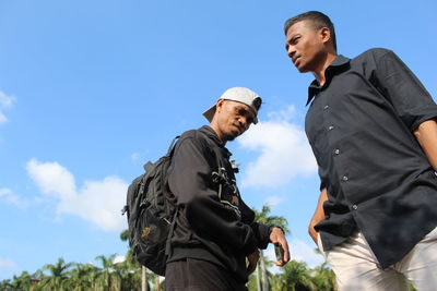 Low angle view of people standing against blue sky