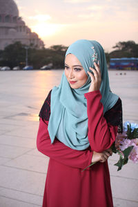 Woman holding flowers while standing against historic building