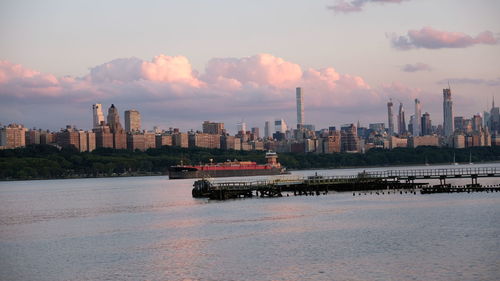 Scenic view of river by buildings against sky during sunset