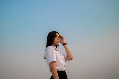 Low angle view of woman standing against clear sky