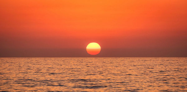 Scenic view of sea against orange sky