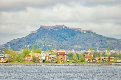 Scenic view of river by buildings against sky