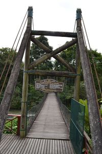 Elevated walkway leading towards suspension bridge against sky