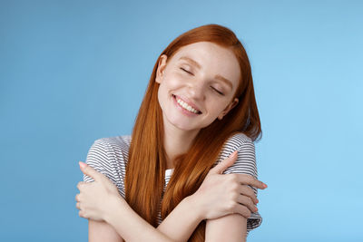 Portrait of a smiling young woman against blue background