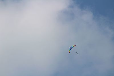 Low angle view of people paragliding against sky