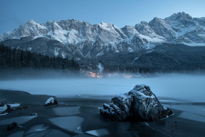 Scenic view of frozen lake by mountains against sky