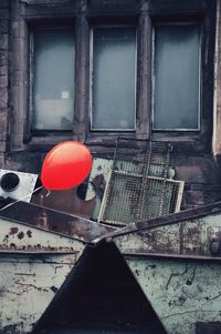 Red balloon on window of abandoned building