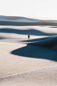Mid distance view of man walking on sand dune