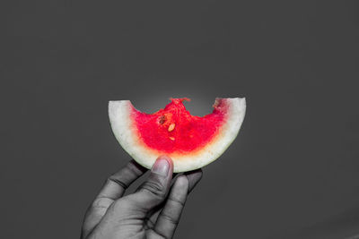 Close-up of hand holding strawberry over black background