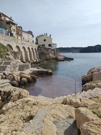 Buildings by sea against sky