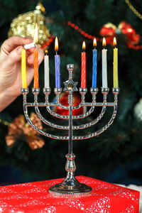 Cropped hand burning candles on menorah