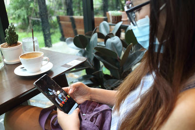 Midsection of woman holding smart phone in cafe