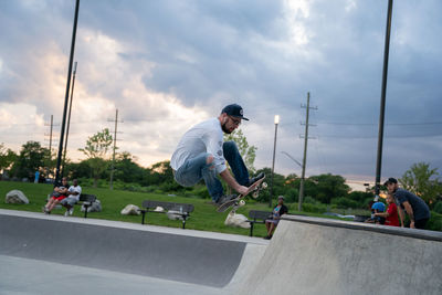 Rear view of man skateboarding on skateboard against sky