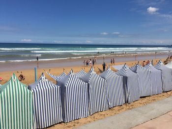 Hooded beach chairs at beach against sky