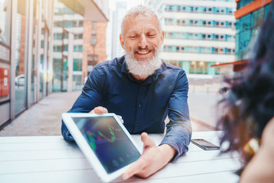 Portrait of man using digital tablet while sitting on table