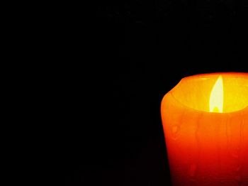 Close-up of lit candle in dark room