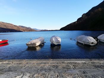 Boats moored in sea against clear sky