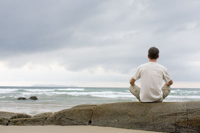 Rear view of man sitting on beach