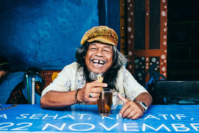 Portrait of a smiling young man sitting on table