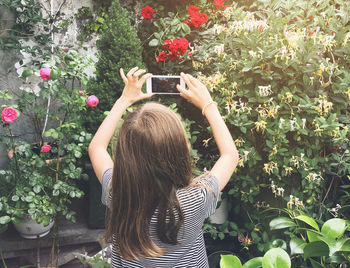 Rear view of girl photographing with mobile phone