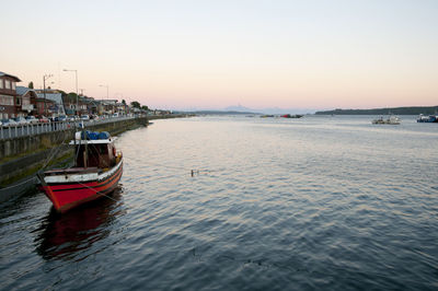 Boats moored at harbor against clear sky