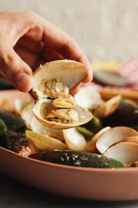 Close-up of hand holding shellfish in plate