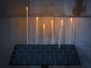 Candles on rack against wall in church